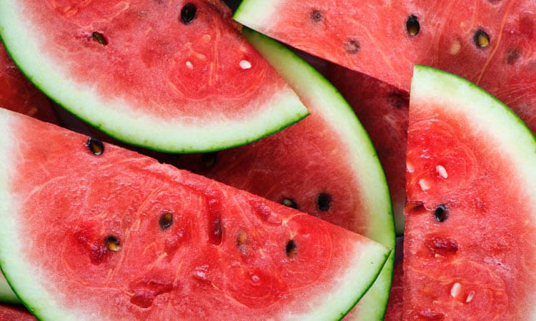 Aerial view of slices of red watermelon with black seeds and green and white rinds for a healthy summertime treat