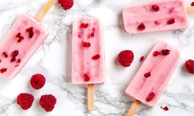 Aerial view of homemade pink popsicles made with raspberries that might cause tooth sensitivity after a dental crown
