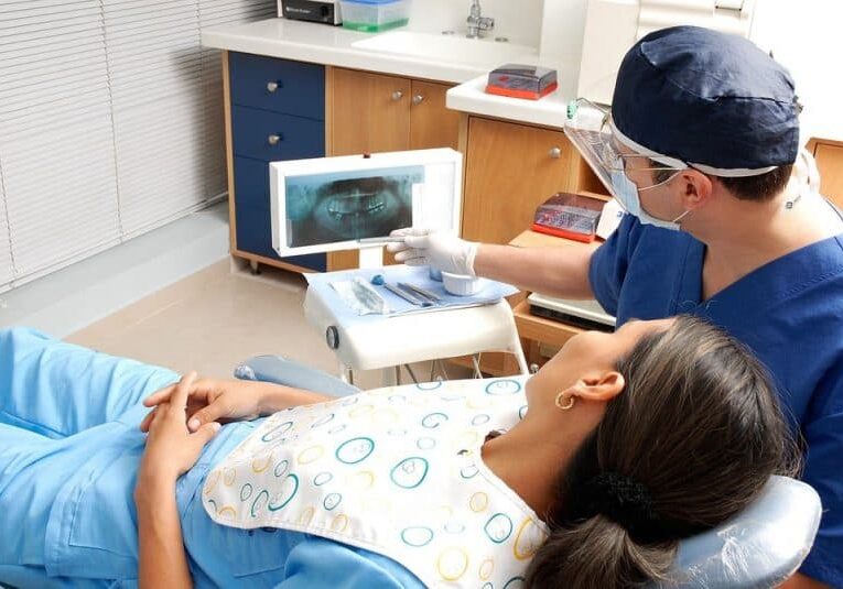 Patient and dentist looking at monitor of dental x-rays
